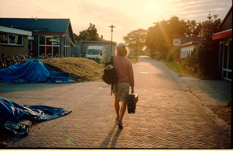 Max Berend walks with his guitar case and backpack on the island of Schiermonnikoog towards a bike shop. Streets of cobblestone and the sun slowly rising above the village. This is the place where he wrote his debut album 'Red Little Paper Kite'.