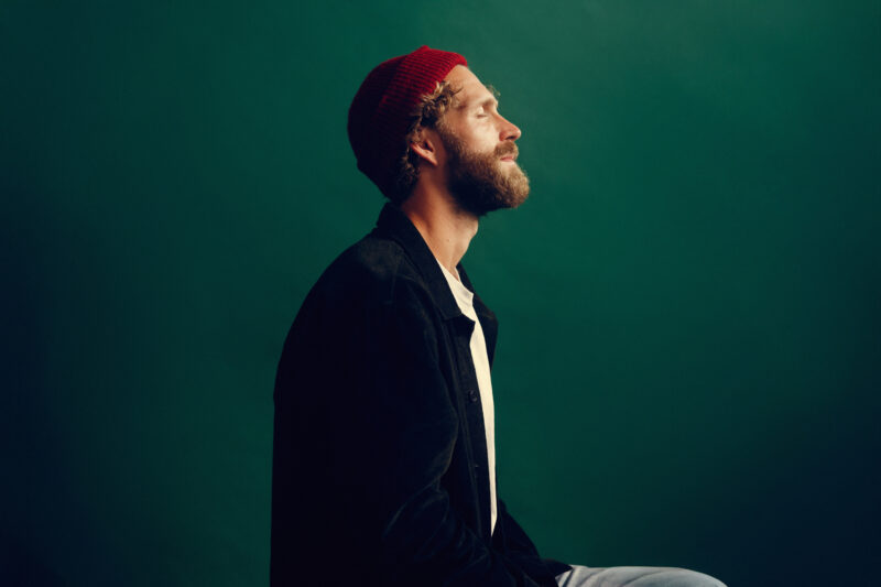 Max Berend, singer-songwriter, with his eyes closed, standing calmly and conveying a sense of serenity, reflecting the theme of his album On Serenity.